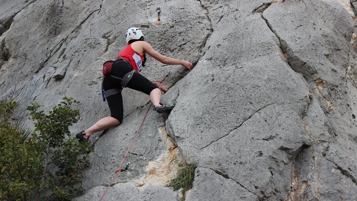 A climber ascends a rugged cliff face in El Chorro, Andalusia, Spain, capturing adventure and skill.